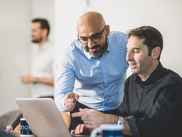 Two Ipanova consultants discussing a laptop screen during a team meeting