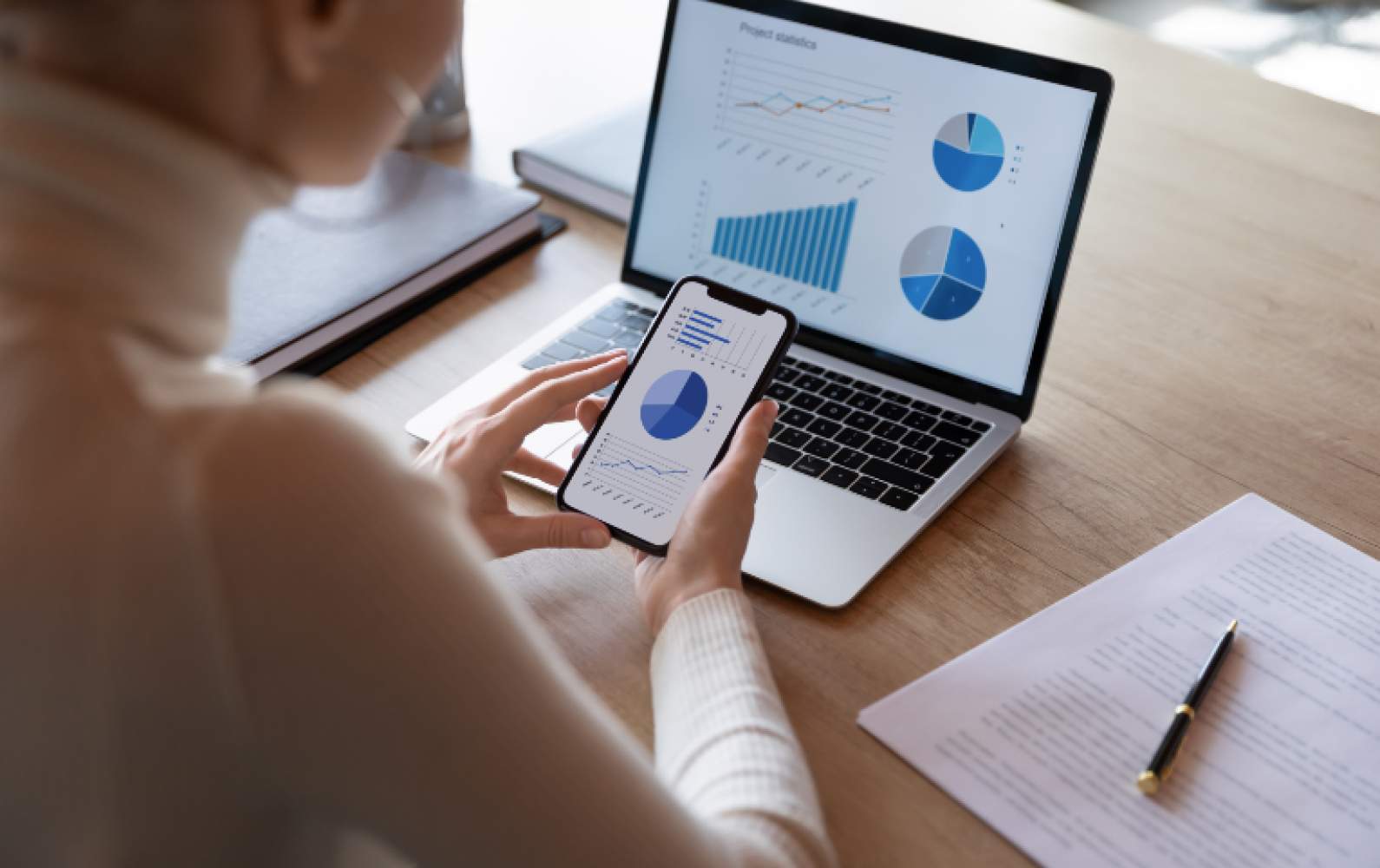 SME manager reviewing Business Intelligence dashboards on a phone and a laptop